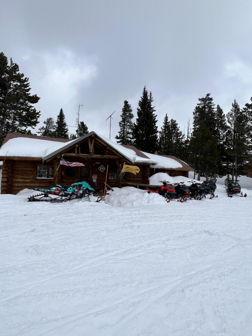 A hut covered with snow and some parked vehicles
